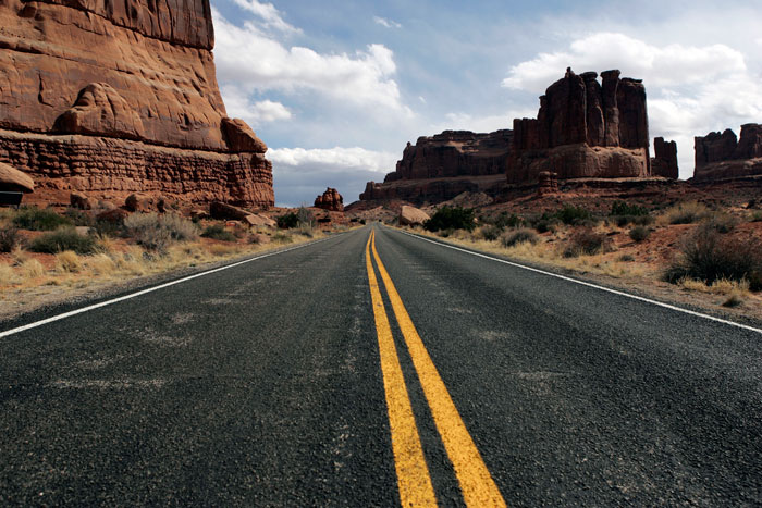Canon EOS 1D MarkII — 24mm ISO 100 @ f/5.6 and 1/250 sec — The roadway carves through the landscape at Arches National Park just outside of Moab, Utah.