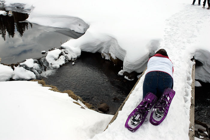 Canon EOS 1D MarkII — 24mm ISO 100 @ f/8 and 1/400 sec — Katie crawls across the snow covered bridge while snowshoeing around Mesa Lakes.