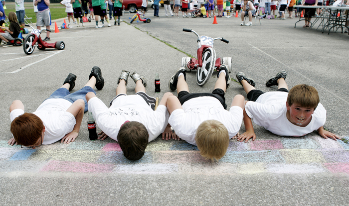 In this May 26, 2010 photo, members of the the No. 23 Dr. Pepper team and winners of the race, from left, Jordan Rhodus, Grant Jessup and Travis Isaacs kiss the chalk-drawn bricks at the Titan 500 while teammate Corbin Pew lifts his head at the end of the Big Wheel tricycle race at Tri Elementary School in Straughn, Ind. (AP Photo/The Courier-Times, Max Gersh) ©2010