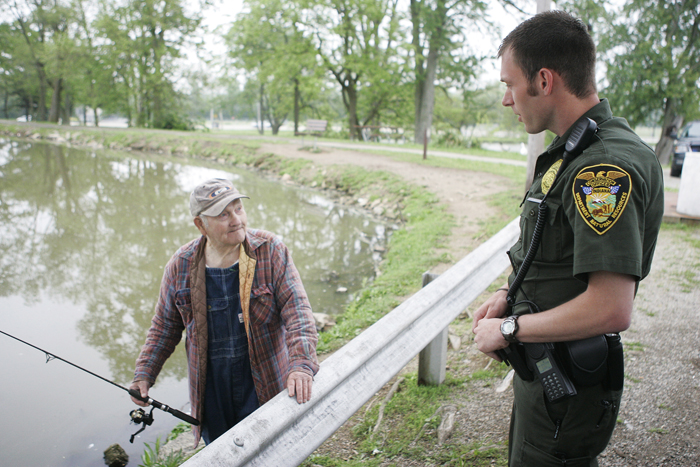 Indiana Conservation Officer Zach Walker, right, talks with New Castle resident Wayman Hoots Wednesday, May 19 in Memorial Park. Walker was checking on Hoots' catch for the day to make sure he was within the legal limit. (C-T photo Max Gersh) ©2010