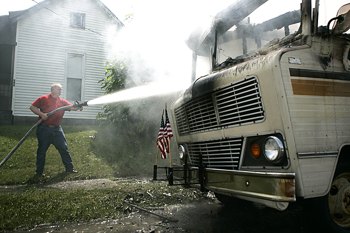 New Lisbon firefighter Eric Keesling finishes extinguishing a Winnebago that burst into flames Monday shortly after the Memorial Day parade in New Castle. Keesling and other members of the New Lisbon Fire Department were headed home when they saw the RV on fire. (C-T photo Max Gersh) ©2010