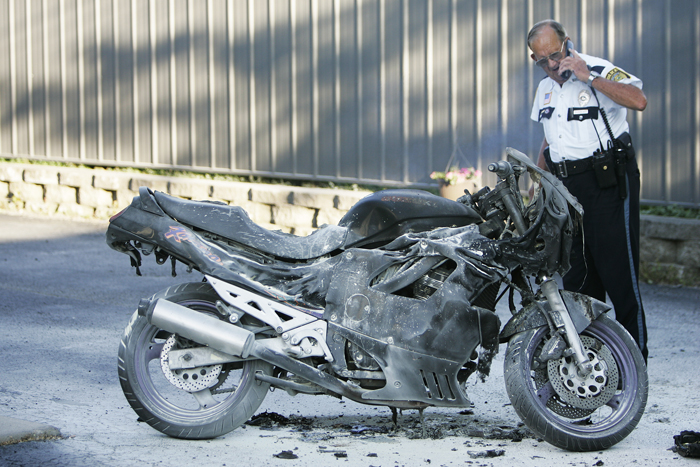Vaughn Reid Jr. looks down at a motorcycle that had caught on fire Thursday night shortly after the bike had been extinguished. The motorcycle was supposed to be sold later the same evening.(C-T photo Max Gersh) ©2010