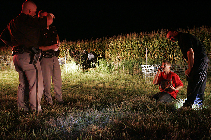 Justin Ryan Pierce, 19, of Mount Summit, talks on his cell phone late Wednesday night after crashing a 1987 Mercedes Benz in a confield near the intersection of Road 300S and Ind. 103. His passenger, Jimmy Luna, 17, New Castle, was flown from the scene to Methodist Hospital in Indianapolis. (C-T photo Max Gersh) ©2010