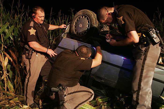 Henry County Sheriff Deputies take down the VIN number off of a 1987 Mercedes Benz late Wednesday night after it wrecked in a cornfield near the intersection of Road 300S and Ind. 103. (C-T photo Max Gersh) ©2010