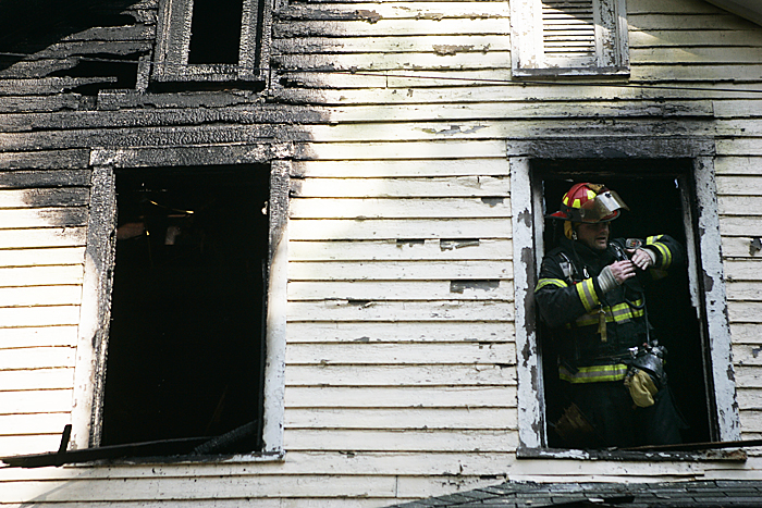 A firefighter communicates out of a second story window with crews on the ground Thursday afternoon while trying to locate hot spots in a home in Spiceland. (C-T photo Max Gersh) ©2010