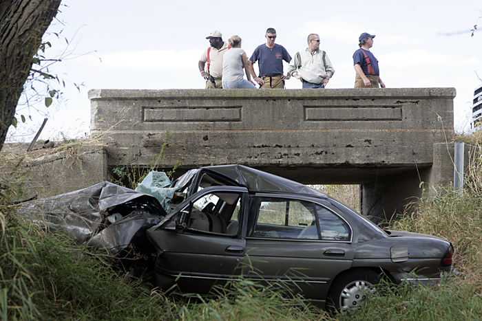 Emergency responders stand on an overpass along County Road 500S Thursday afternoon after a vehicle occupied by two 16-year-old girls left the roadway and landed in a small creek bed. (C-T photo Max Gersh) ©2010