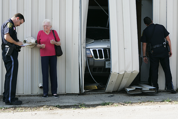 Opal Dixon talks with Sgt. Adrian Darwin after her Jeep went through a building Monday afternoon while backing down her driveway. (C-T photo Max Gersh) ©2010