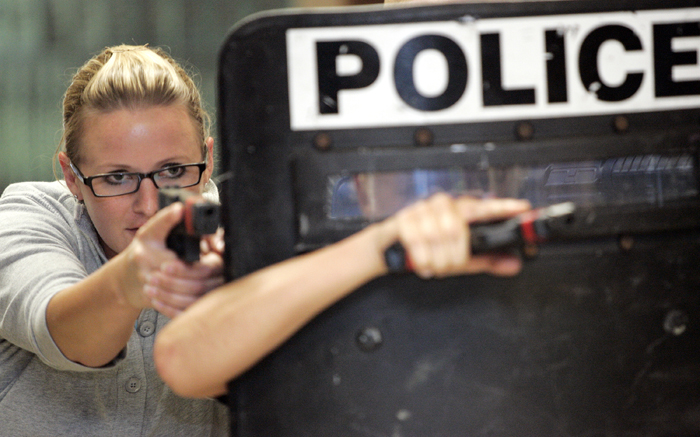 MAX GERSH | ROCKFORD REGISTER STAR Adrienne Horn of the Rock Valley College Police Department takes cover behind a shield Wednesday, Aug. 10, 2011, during rapid deployment to an active shooter training at Harlem High School in Machesney Park. ©2011