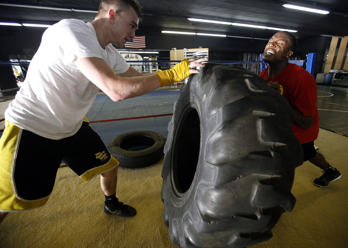 Ryan Newman (left), 20, and Joshua Patterson, 24, push a tire back and forth during a "standing pushup" exercise Tuesday, April 30, 2013, at Fight College on North Main Street in Rockford. MAX GERSH/ROCKFORD REGISTER STAR ©2013