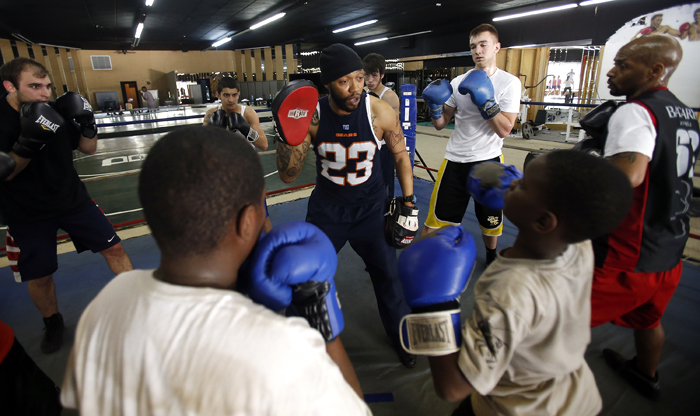 Tony Bandy (center) holds up a target as he is surrounded by boxing students Tuesday, April 30, 2013, at Fight College on North Main Street in Rockford. MAX GERSH/ROCKFORD REGISTER STAR ©2013